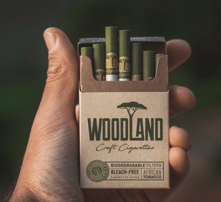 A packet of Woodland Craft Cigarettes. They have biodegradable filters, unbleached cigarette paper, and tobacco without artificial additives. It is an eco conscious cigarette product, but still bad for one's health. Held by a smoker that is out in nature. Eine Packung Woodland Craft Zigaretten. Sie haben biologisch abbaubare Filter, ungebleichtes Zigarettenpapier und Tabak ohne künstliche Zusatzstoffe. Es handelt sich um ein umweltbewusstes Zigarettenprodukt, das jedoch immer noch schädlich für die Gesundheit ist. Gehalten von einem Raucher, der sich in der Natur befindet.